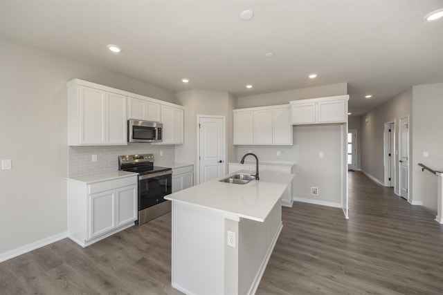 kitchen featuring an island with sink, a sink, dark wood-style floors, white cabinetry, and appliances with stainless steel finishes