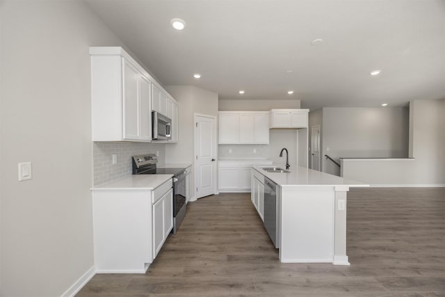 kitchen featuring wood finished floors, a sink, decorative backsplash, stainless steel appliances, and white cabinets