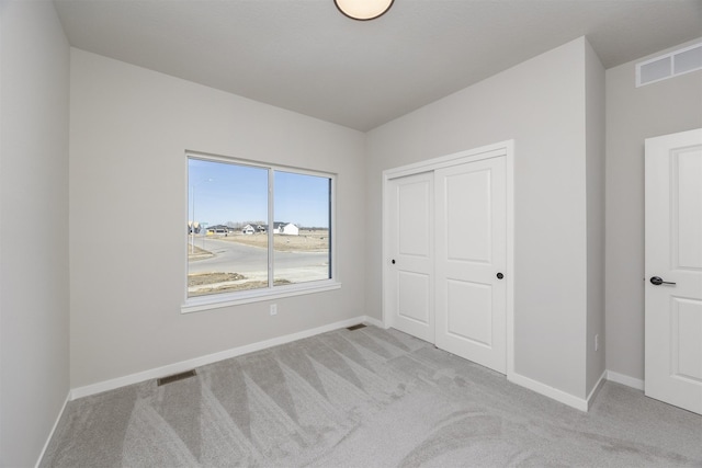 unfurnished bedroom featuring visible vents, light carpet, baseboards, and a closet