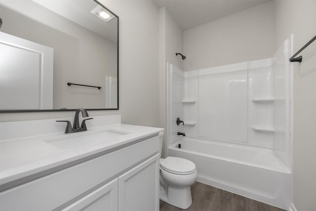 bathroom featuring vanity, toilet, wood finished floors, and shower / washtub combination