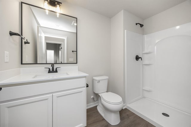 bathroom featuring vanity, wood finished floors, toilet, and a shower