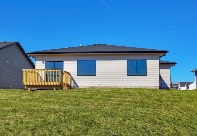 rear view of property featuring a wooden deck and a lawn