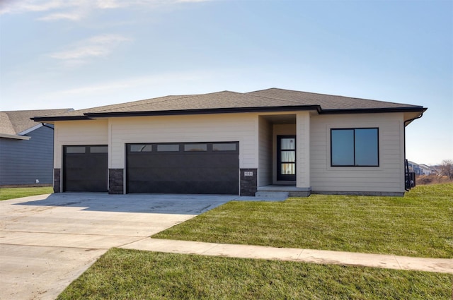 prairie-style home featuring concrete driveway, a garage, roof with shingles, and a front lawn