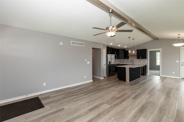 kitchen featuring light hardwood / wood-style floors, stainless steel fridge, vaulted ceiling with beams, and a kitchen island