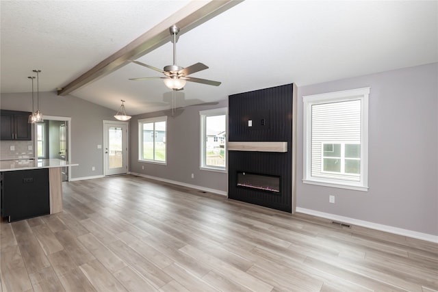 unfurnished living room with ceiling fan, a textured ceiling, a fireplace, light hardwood / wood-style floors, and lofted ceiling with beams