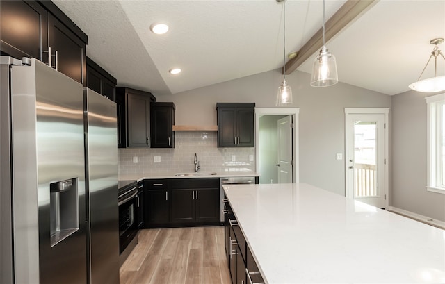 kitchen with light wood-type flooring, lofted ceiling with beams, stainless steel appliances, pendant lighting, and decorative backsplash