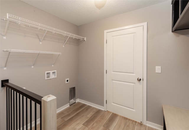 clothes washing area with light hardwood / wood-style floors, hookup for an electric dryer, a textured ceiling, and washer hookup