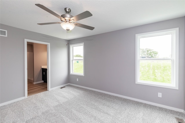 unfurnished bedroom with ensuite bath, carpet flooring, a textured ceiling, and ceiling fan