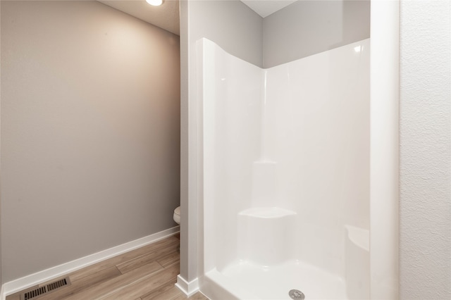 bathroom featuring hardwood / wood-style floors, a shower, and toilet