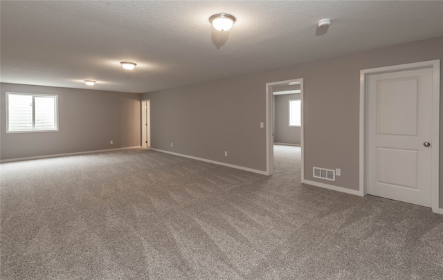 carpeted empty room featuring a textured ceiling