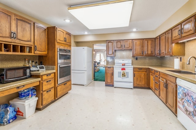 kitchen featuring decorative backsplash, sink, and white appliances