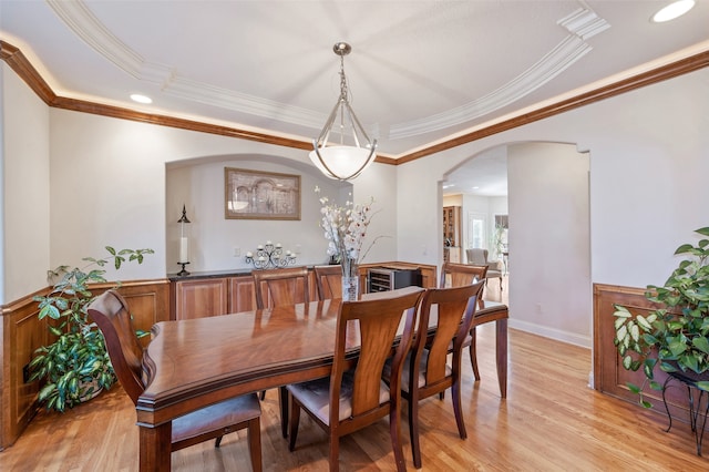 dining room with crown molding, light hardwood / wood-style floors, and a raised ceiling