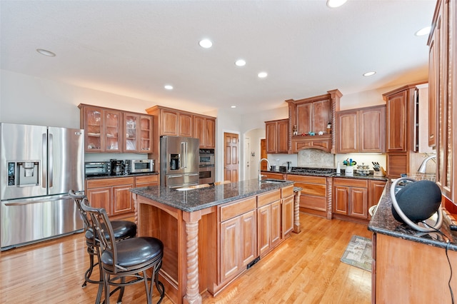 kitchen featuring a kitchen breakfast bar, stainless steel appliances, a center island with sink, sink, and light hardwood / wood-style floors