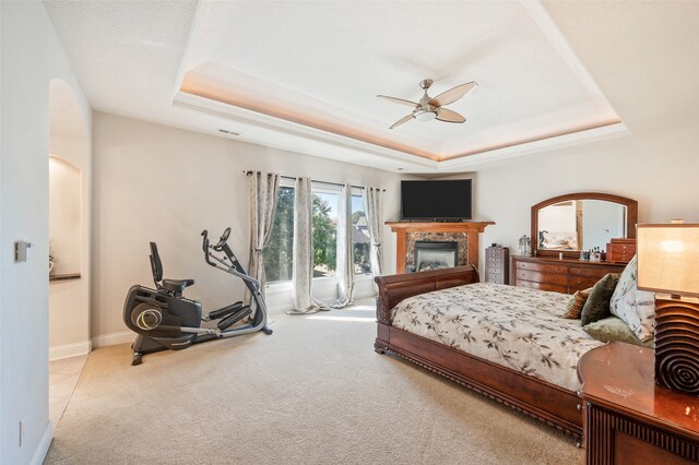 carpeted bedroom with ceiling fan and a raised ceiling