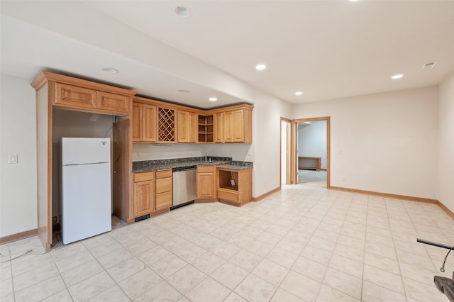 kitchen featuring white fridge, dark stone counters, and stainless steel dishwasher