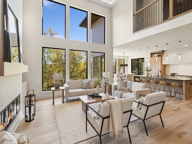 living room with a towering ceiling, light hardwood / wood-style flooring, and sink