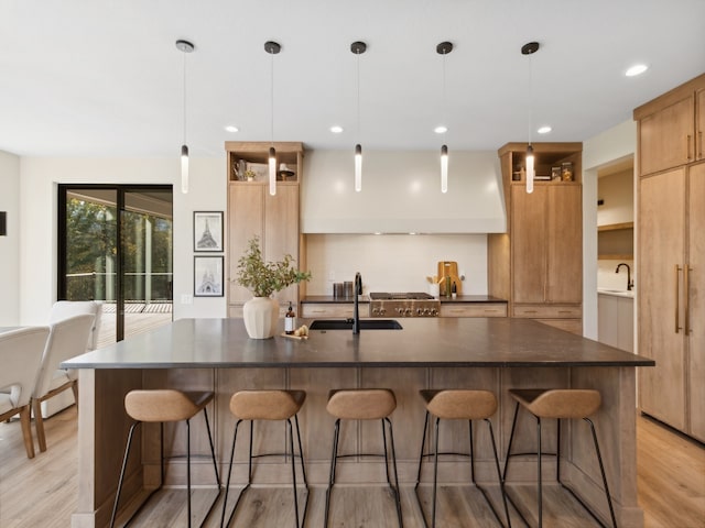 kitchen with decorative light fixtures, light hardwood / wood-style flooring, a spacious island, and sink