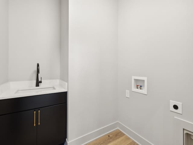 clothes washing area with electric dryer hookup, cabinets, sink, hookup for a washing machine, and light hardwood / wood-style flooring