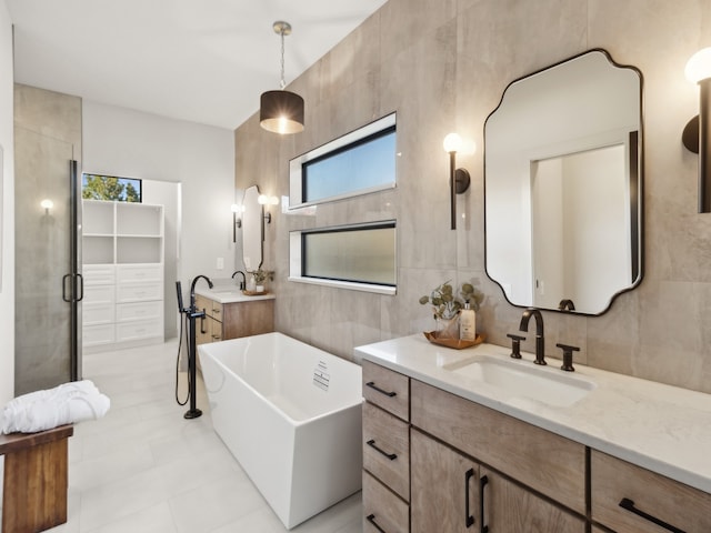 bathroom with vanity, a tub to relax in, plenty of natural light, and tile walls