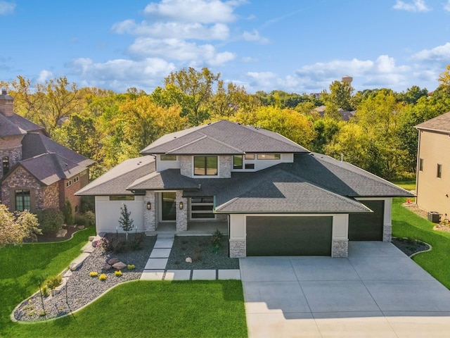 view of front of property featuring a front yard, central AC, and a garage