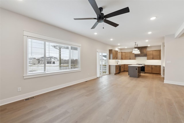 unfurnished living room featuring ceiling fan, light wood-type flooring, and sink