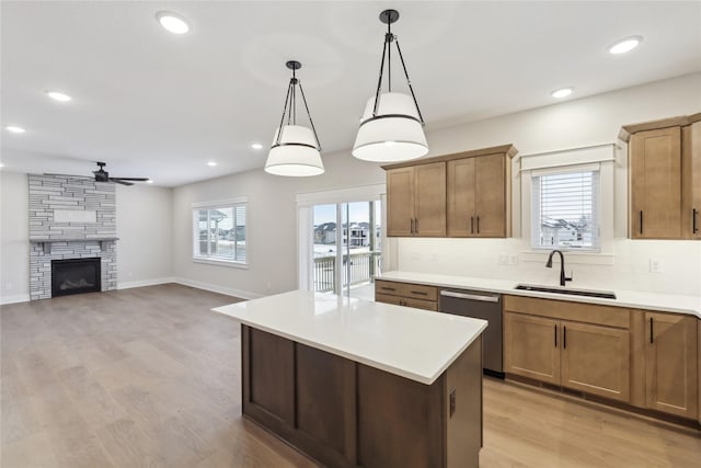 kitchen with a wealth of natural light, sink, dishwasher, a center island, and hanging light fixtures