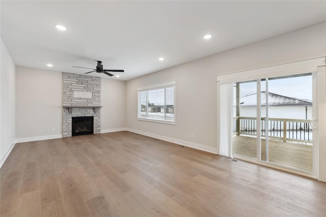 unfurnished living room with ceiling fan, a fireplace, and light hardwood / wood-style flooring