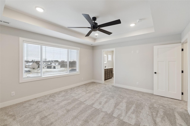 carpeted empty room with a raised ceiling and ceiling fan