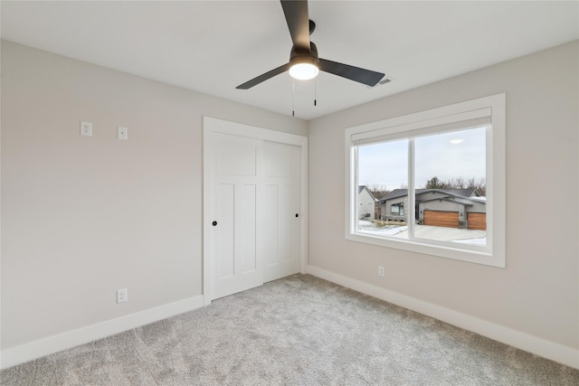 unfurnished bedroom featuring ceiling fan, a closet, and light carpet