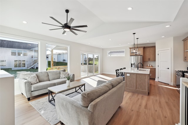 living room with light hardwood / wood-style flooring, vaulted ceiling, sink, and ceiling fan