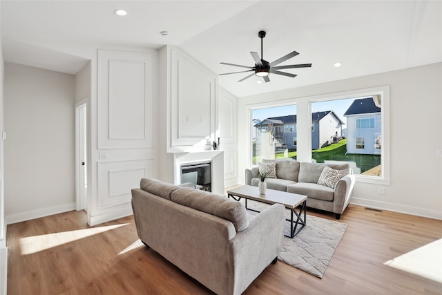 living room with vaulted ceiling, light hardwood / wood-style flooring, and ceiling fan