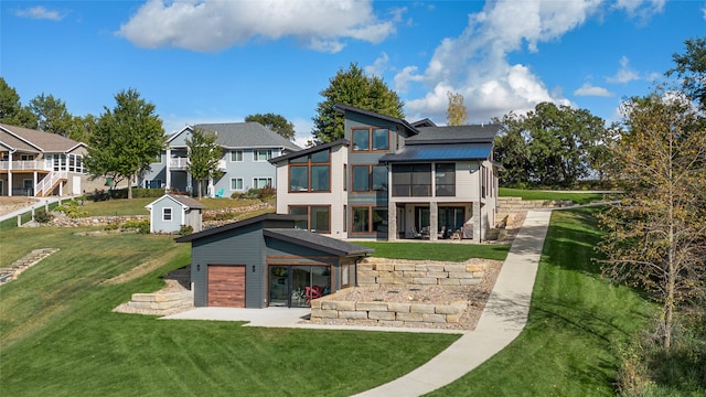 rear view of property with an outdoor structure, a sunroom, and a lawn