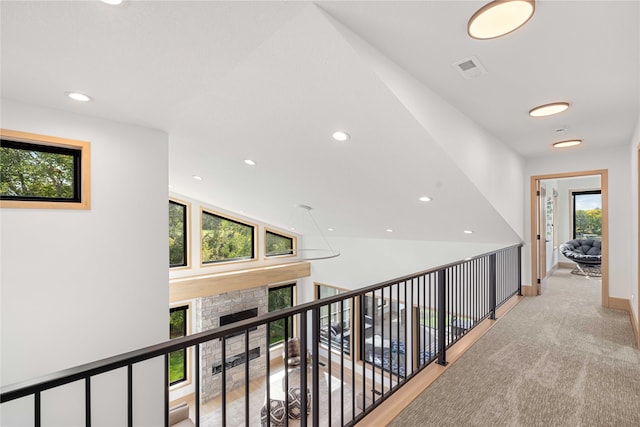 corridor featuring vaulted ceiling, a wealth of natural light, and light colored carpet