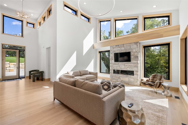 living room with a notable chandelier, a high ceiling, and light wood-type flooring