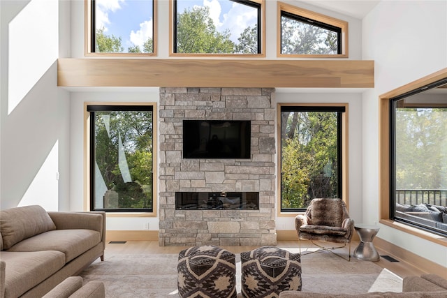 living room featuring high vaulted ceiling, a fireplace, light wood-type flooring, and plenty of natural light