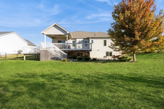 rear view of house featuring a wooden deck and a lawn