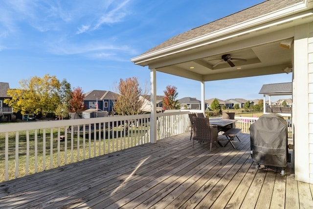 wooden deck with area for grilling, ceiling fan, and a yard