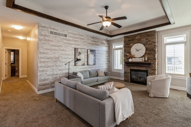 living room featuring ceiling fan, carpet, a tray ceiling, and a fireplace