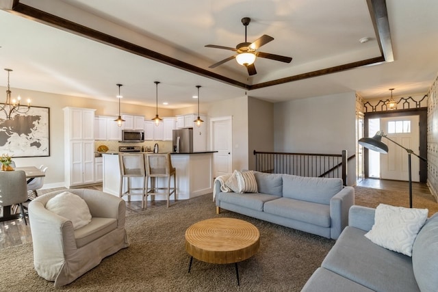 living room featuring hardwood / wood-style floors, a tray ceiling, and ceiling fan with notable chandelier