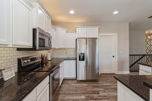 kitchen with white cabinetry, stainless steel appliances, dark wood-type flooring, dark stone countertops, and decorative backsplash