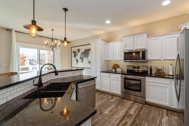 kitchen featuring appliances with stainless steel finishes, white cabinets, sink, and decorative light fixtures