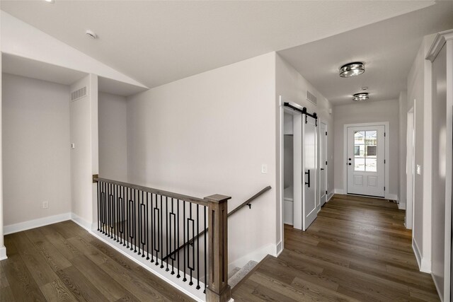 hallway featuring dark wood-type flooring and a barn door