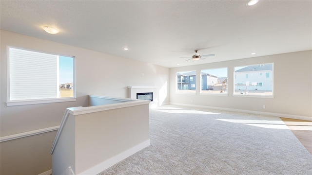 interior space with ceiling fan, light colored carpet, and a healthy amount of sunlight