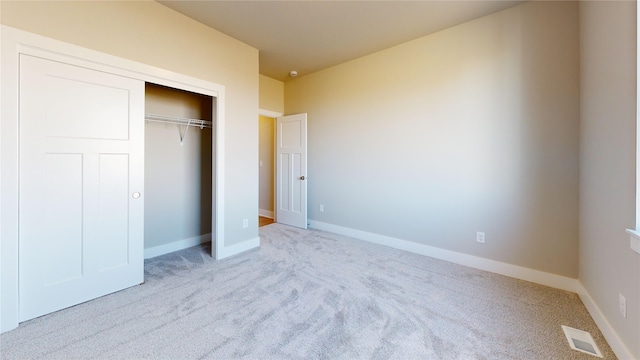 unfurnished bedroom featuring light colored carpet and a closet