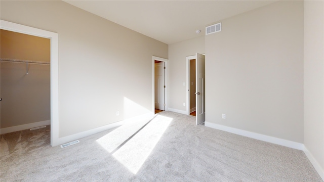 unfurnished bedroom featuring a spacious closet and light carpet