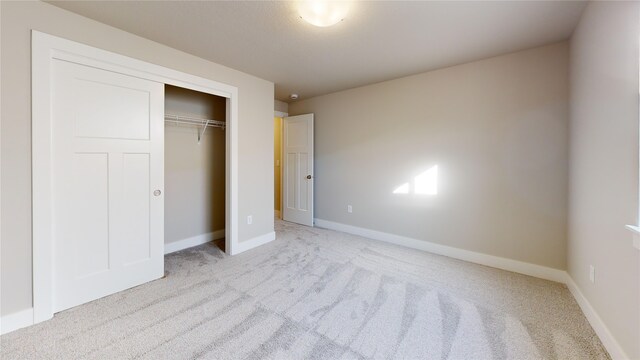 unfurnished bedroom with light carpet and a closet