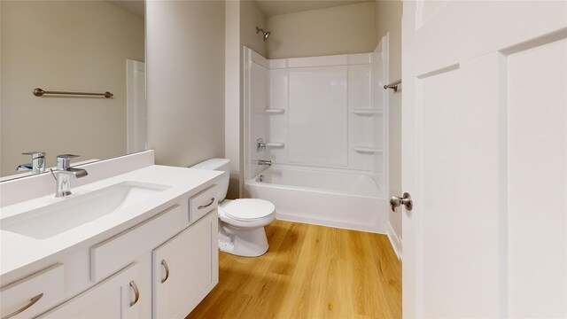 full bathroom with wood-type flooring, toilet,  shower combination, and vanity