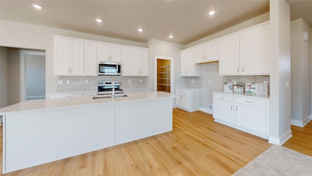 kitchen featuring stainless steel appliances, sink, a kitchen island with sink, and white cabinets