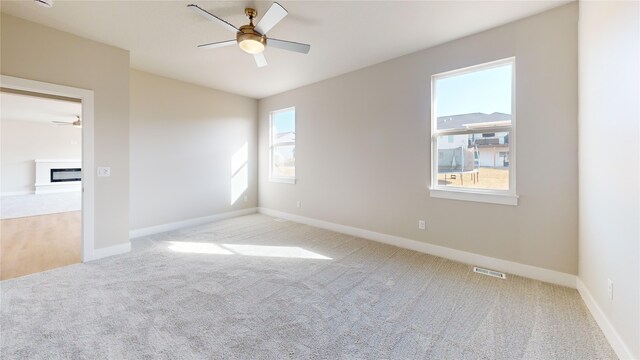 empty room featuring ceiling fan and light colored carpet