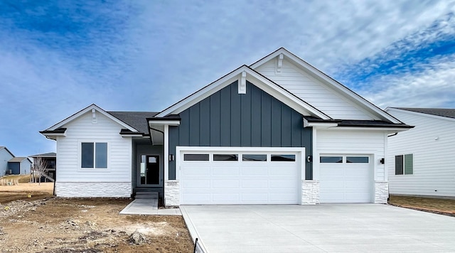 view of front of house featuring a garage, driveway, board and batten siding, and stone siding